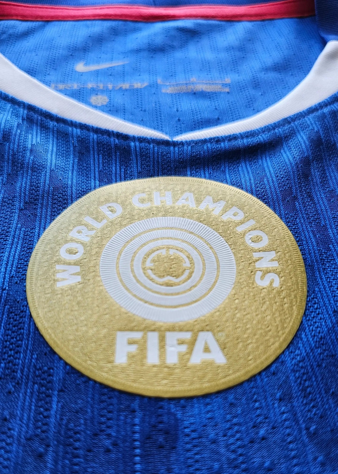 Close-up view of the FIFA World Champions badge on a blue football shirt.