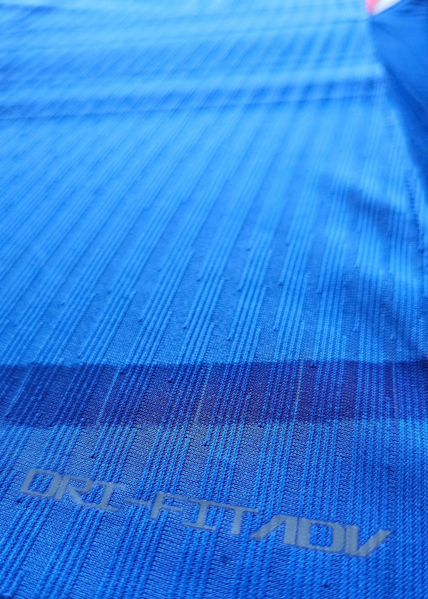 Detail of blue fabric showing ORI-FITADV text on the signed Jorrel Hato Chelsea shirt.