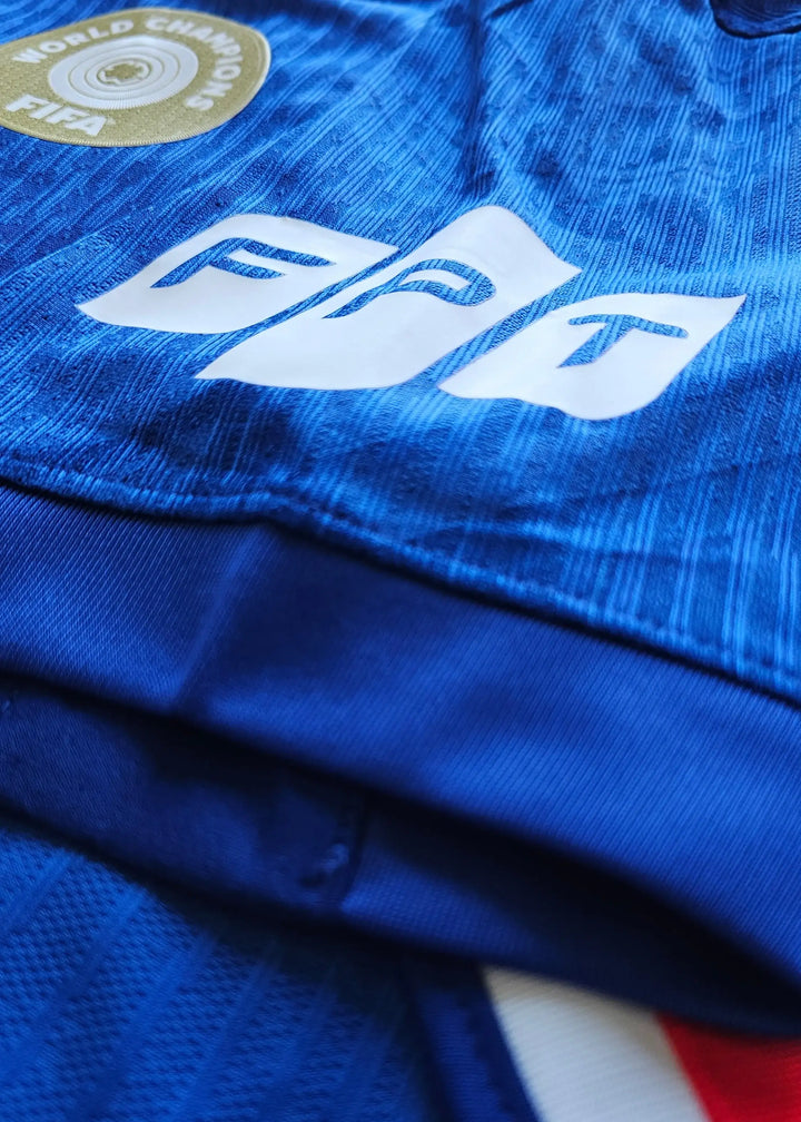 Detailed view showing the FPT logo and FIFA World Champions badge on a blue football shirt.