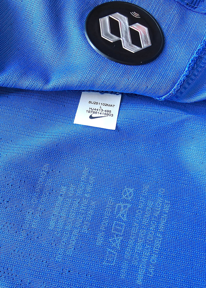 Close-up of blue football shirt showing Nike logo and size label details.