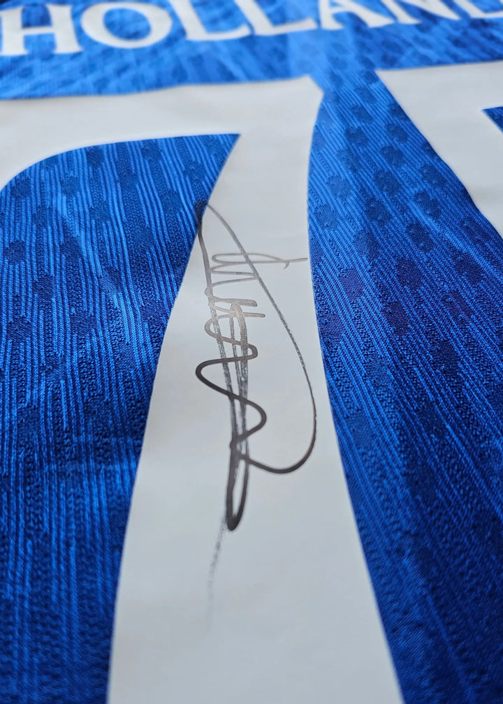 Charlie's signature on a blue No. 75 Chelsea football shirt showing textured fabric detail.