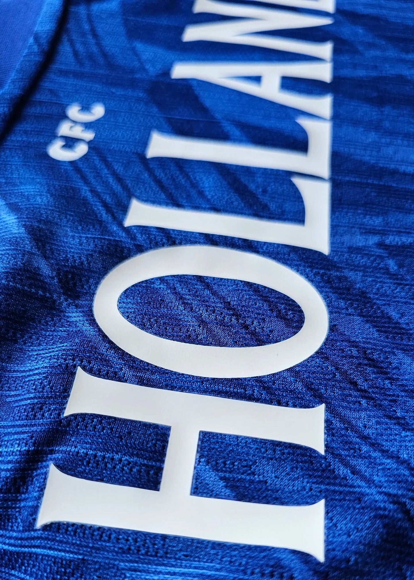 Close-up view showing the name 'HOLLAND' and 'CFC' on a blue football shirt.