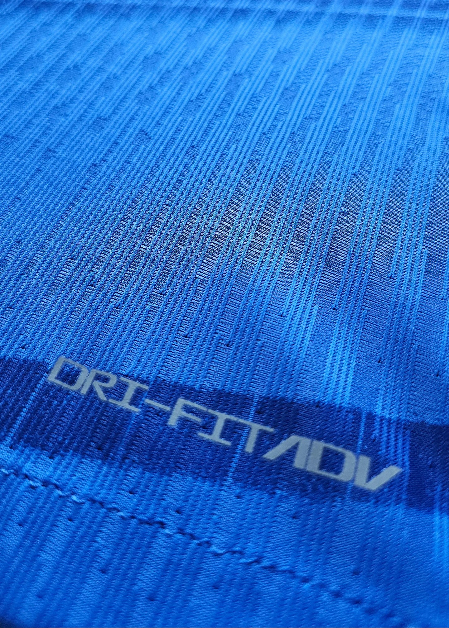 Close-up of the fabric showing textured blue pattern and 'DRI-FIT ADV' text.
