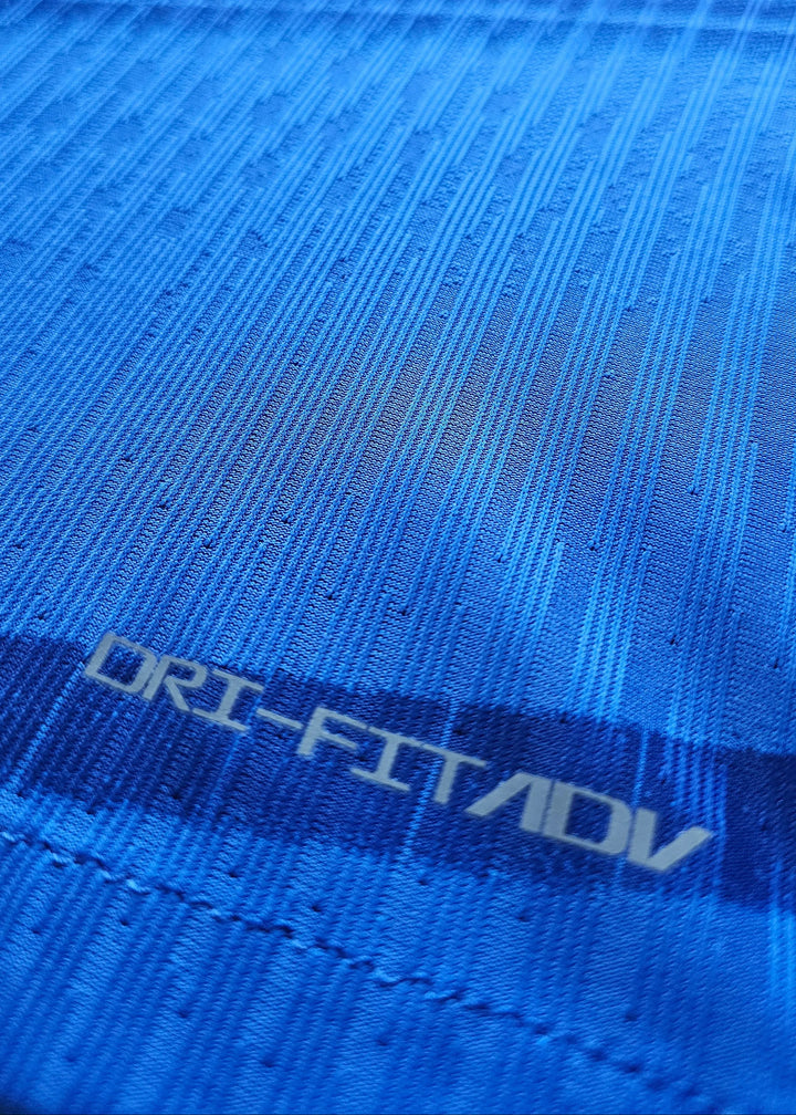 Close-up of the fabric showing textured blue pattern and 'DRI-FIT ADV' text.