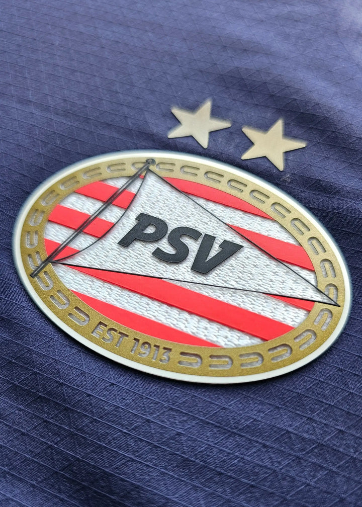 Crest of PSV with two stars and Est. 1913, featuring red stripes and a prominent PSV logo.