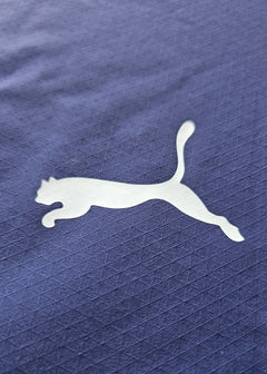 Close-up of white Puma logo on navy fabric with a textured pattern.