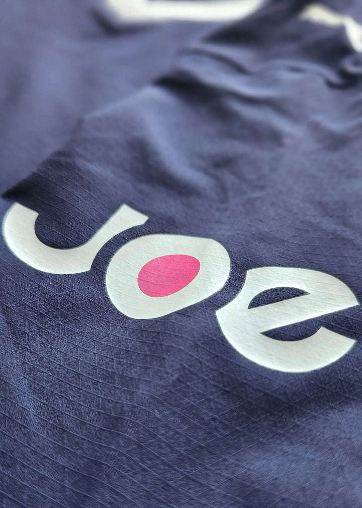 Detail showing the 'Joe' wordmark in white and pink against a navy background.