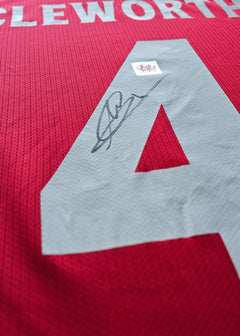 Detail view showing the signature and No. 4 on a red Wrexham A.F.C. football shirt.