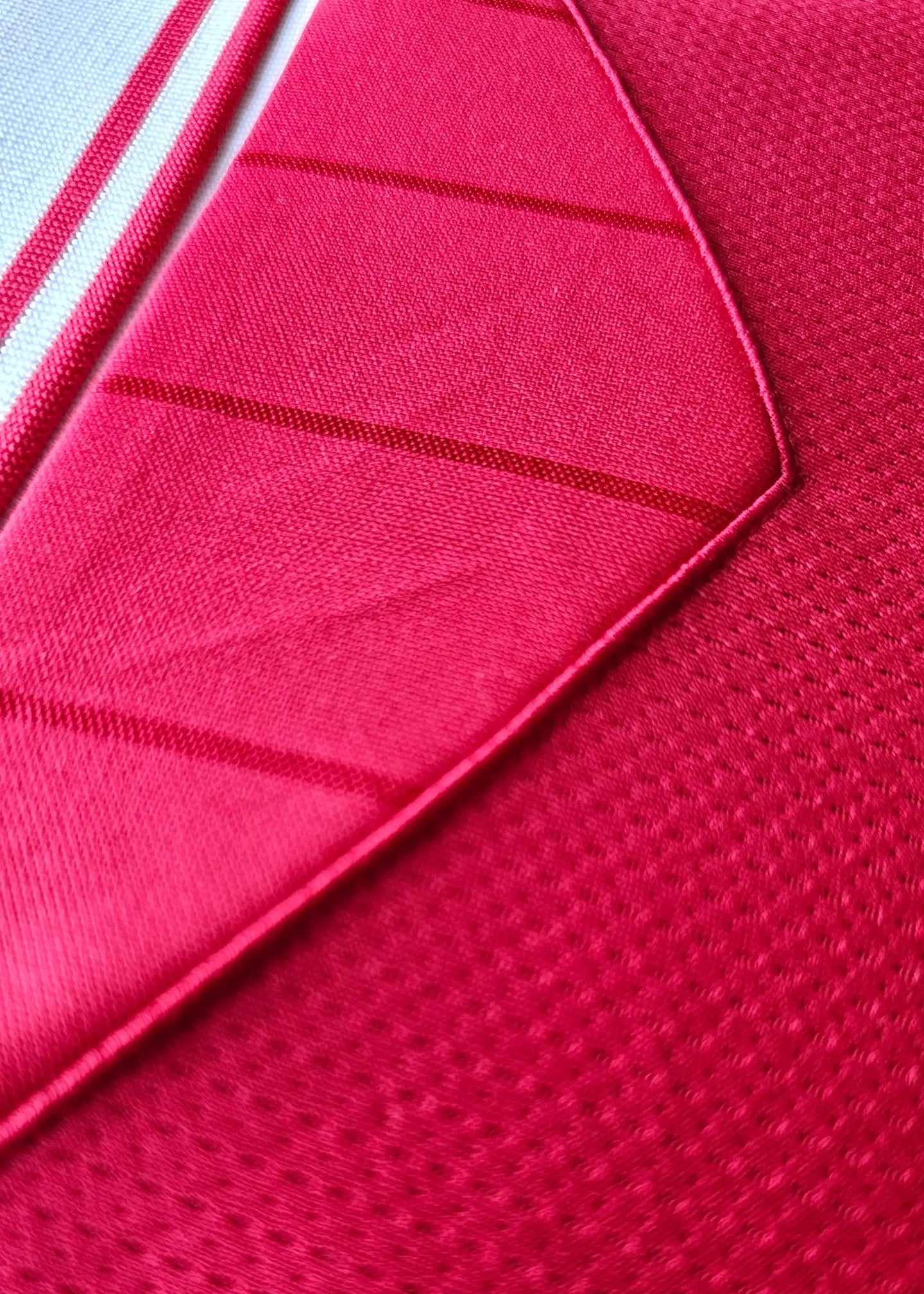 Close-up detail showcasing red fabric and stitching of the signed football shirt.