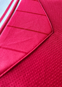 Close-up detail showcasing red fabric and stitching of the signed football shirt.
