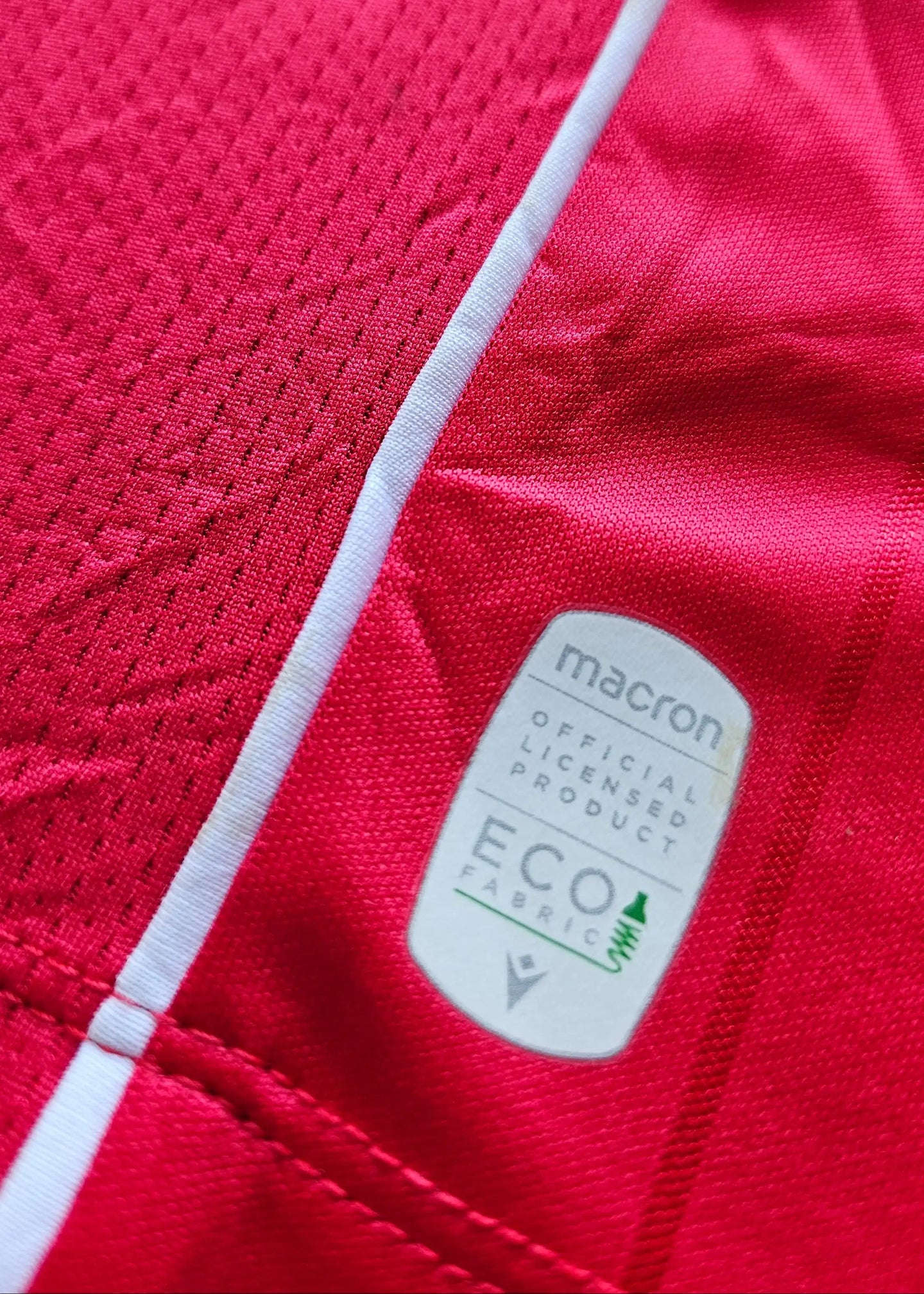 Red fabric with macron tag stating "OFFICIAL LICENSED PRODUCT ECO FABRIC."