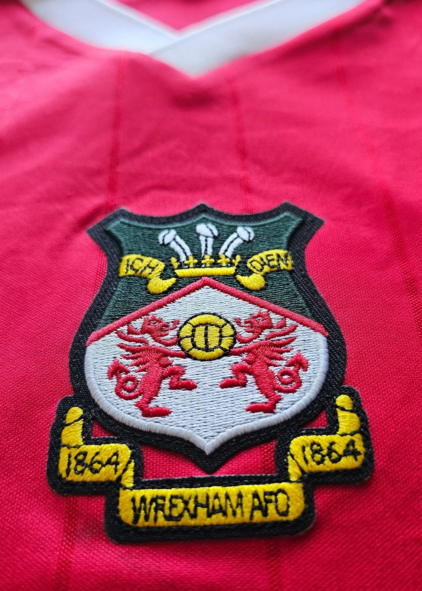 Crest detail featuring Wrexham A.F.C. badge with two red dragons and gold accents on a red background.