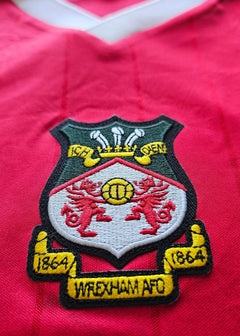 Crest detail featuring Wrexham A.F.C. badge with two red dragons and gold accents on a red background.