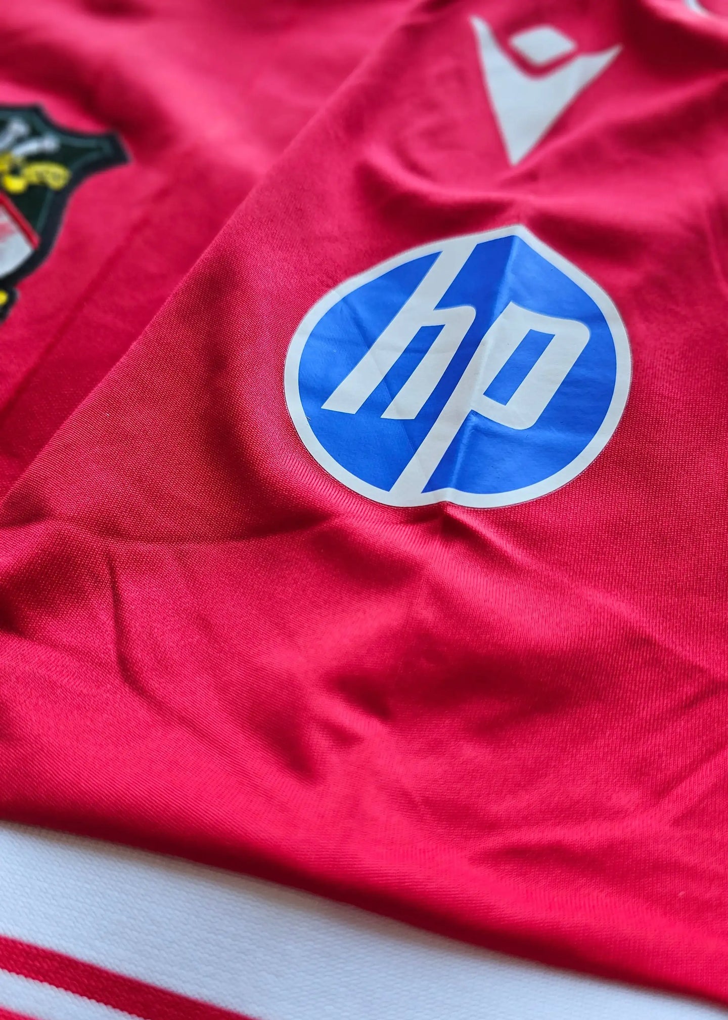 Detail view highlighting the HP sponsor logo on the red football shirt with a white trim.