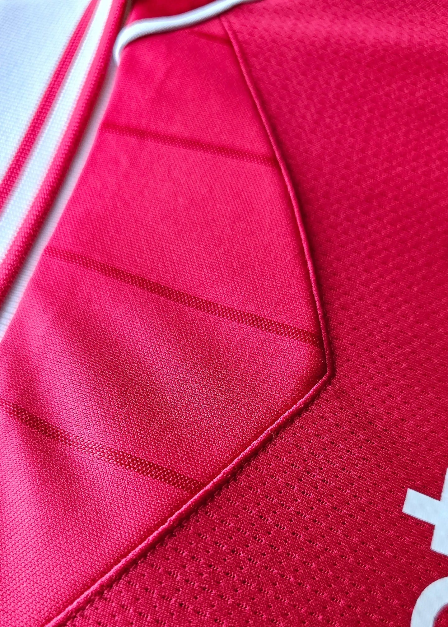 Close-up view of a red football shirt showing fabric texture and stitching details.
