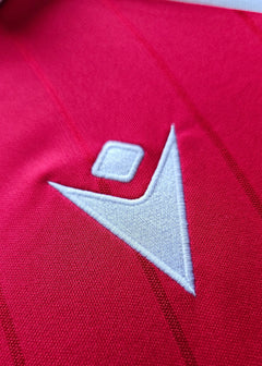 Close-up of the white embroidered logo on the red shirt fabric.