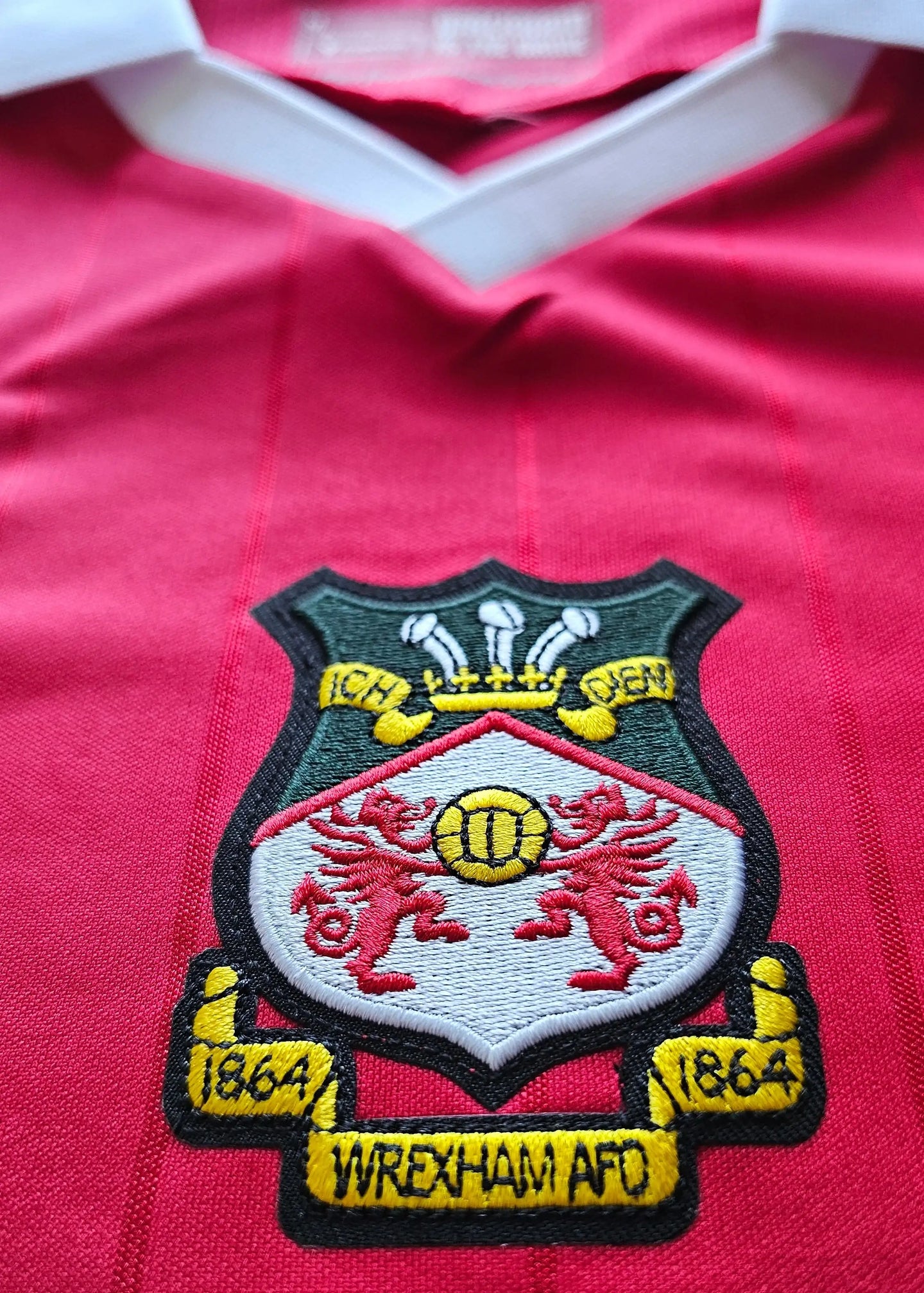 Crest detail featuring Wrexham A.F.C. badge with two lions, year '1864', and three crowns above.