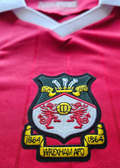 Crest detail featuring Wrexham A.F.C. badge with two lions, year '1864', and three crowns above.