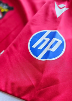 Close-up view of the HP sponsor logo on a pink football shirt.