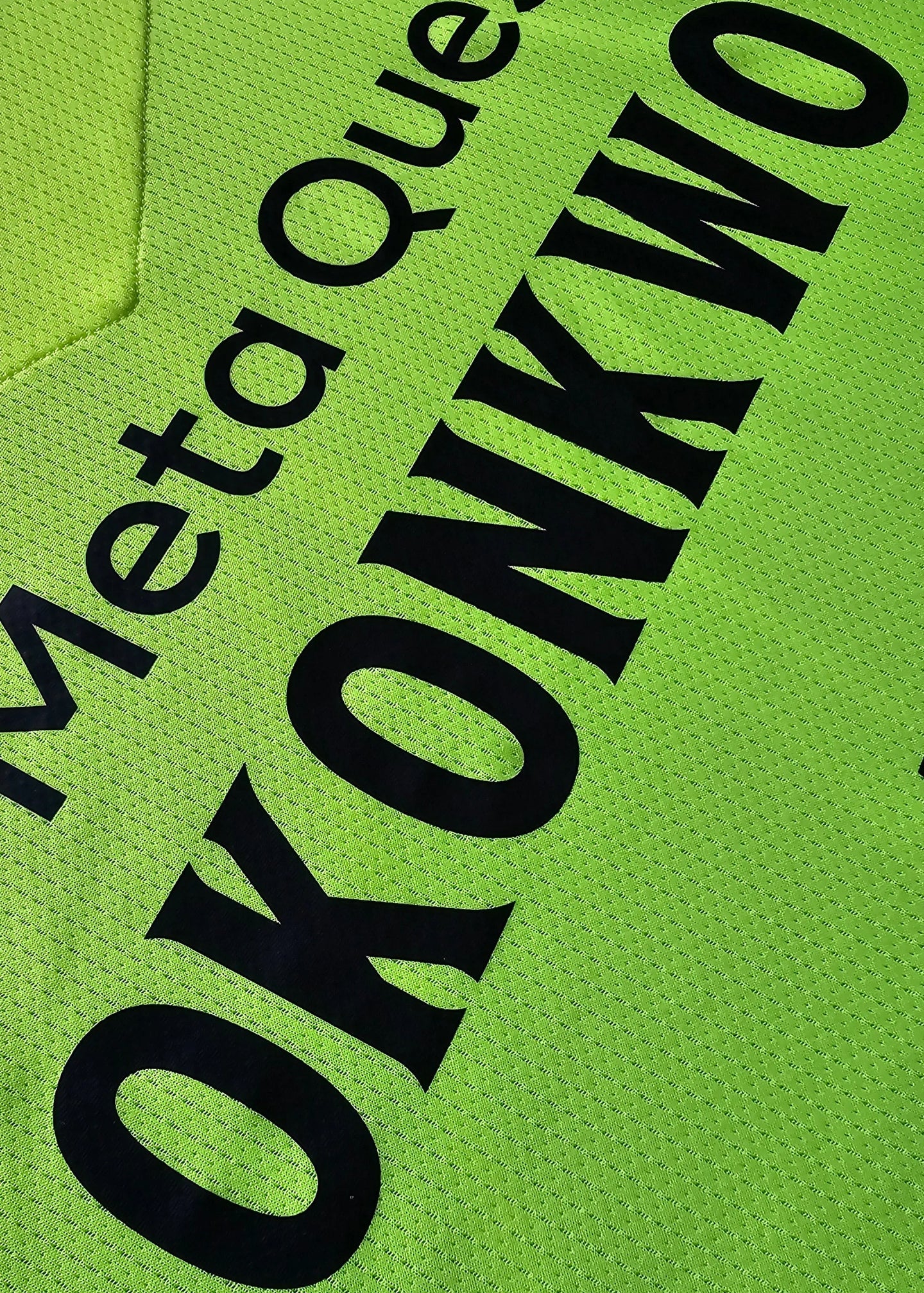 Close-up detail showing the name 'OKONKWO' in black on a bright green football shirt.