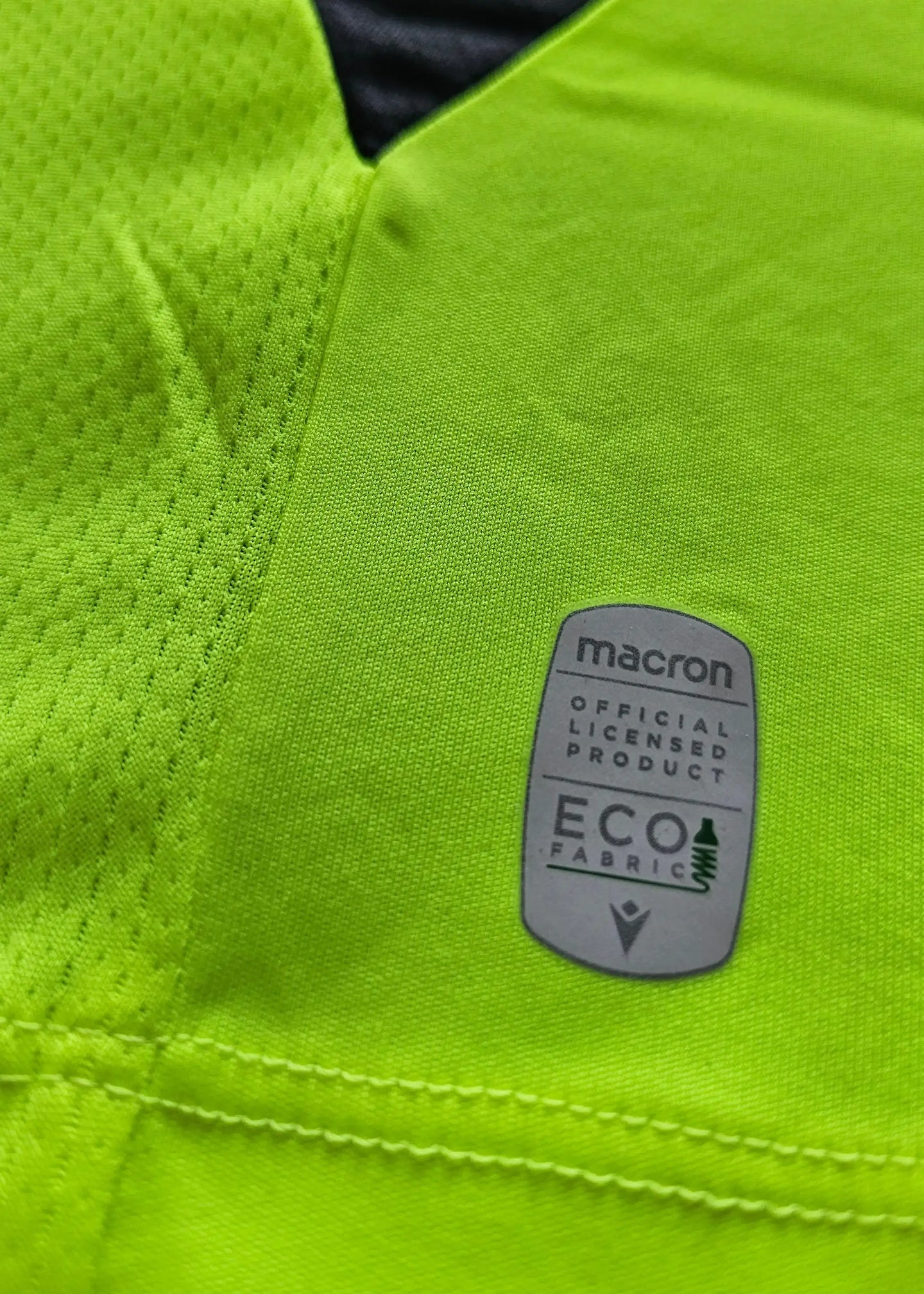 Detail view featuring the Macron label indicating Eco Fabric and licensed product status.