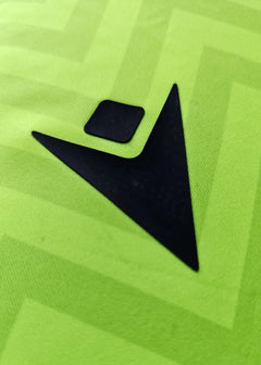 Close-up of black brand logo detail on green football shirt fabric.