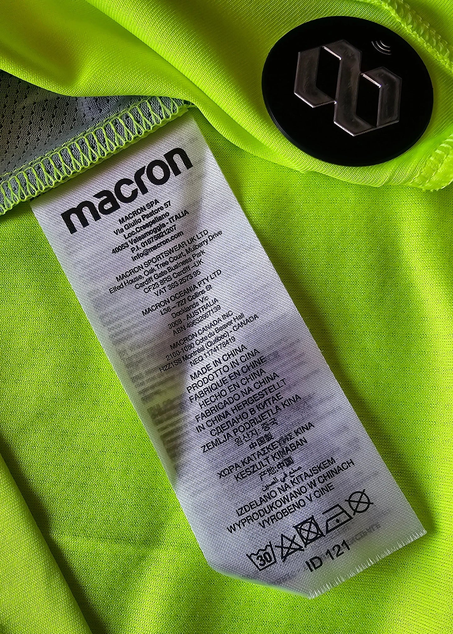 Care label detail showing brand 'macron' and washing instructions on bright green fabric.