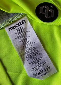 Care label detail showing brand 'macron' and washing instructions on bright green fabric.
