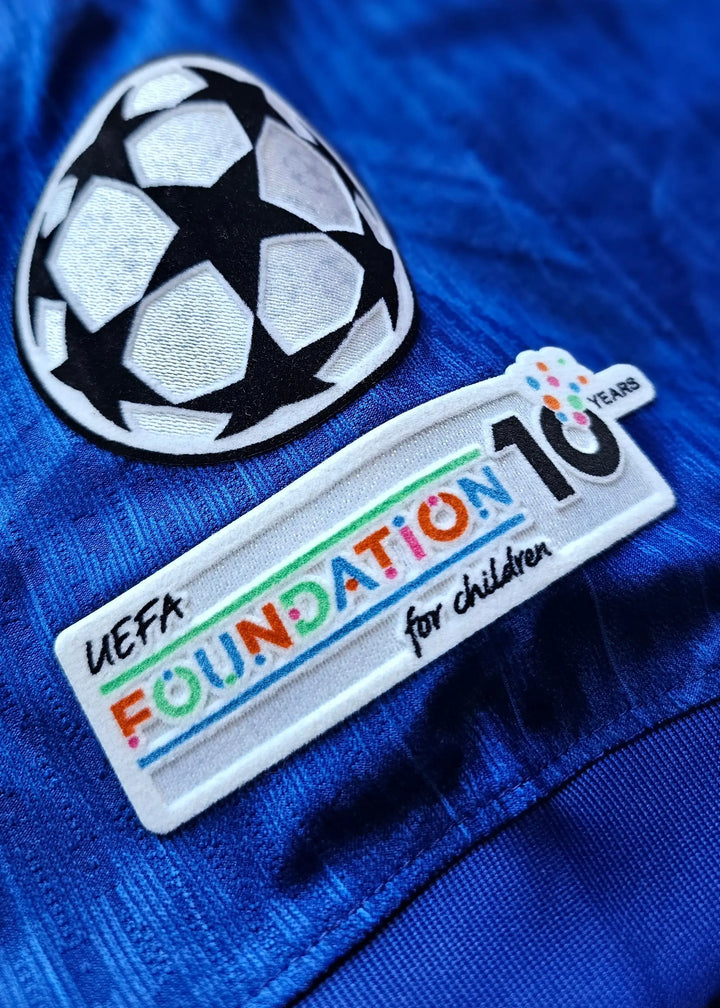 Close-up of UEFA Foundation for Children patch, showing 10 years and football ball design on blue fabric.