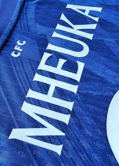 Close-up of the back showing the name MHEUKA and the CFC crest in blue fabric.