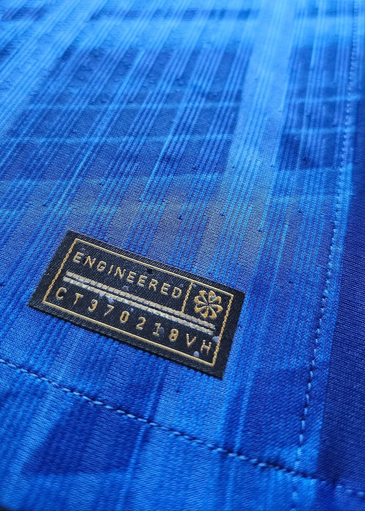 Close-up detail of a blue fabric with 'ENGINEERED' tag and code 'CT970218VH'.