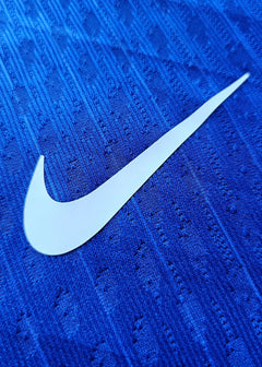 Close-up of the white Nike swoosh on a blue football shirt fabric.