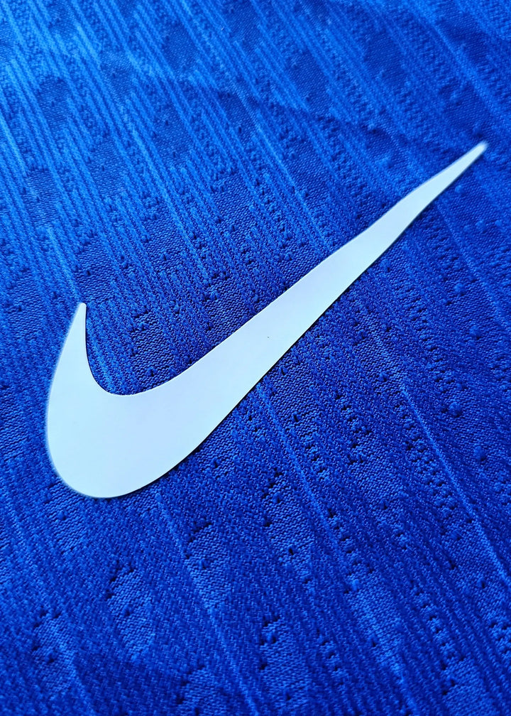 Close-up of the white Nike swoosh on a blue football shirt fabric.