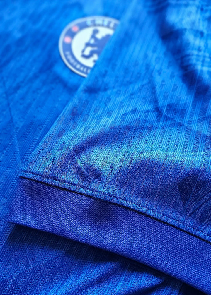 Crest detail featuring Chelsea F.C. logo on a blue football shirt.