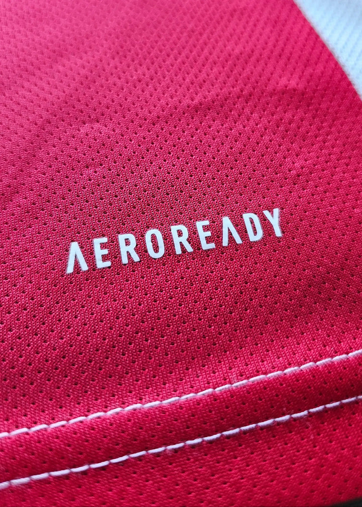 Close-up of AEROREADY logo on red fabric with white stitching details.