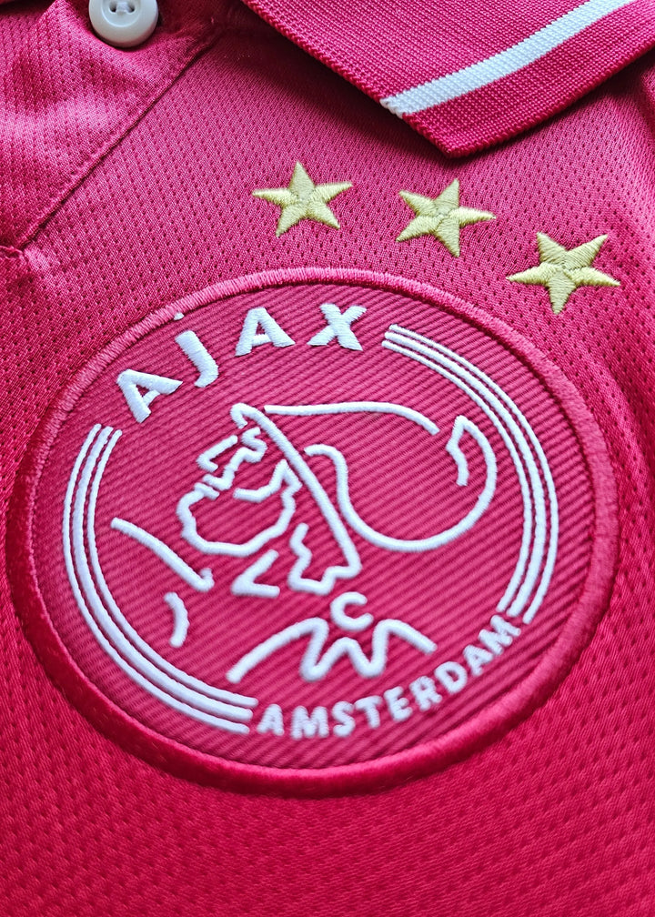 Crest detail with Ajax badge featuring three stars and AMSTERDAM in white embroidery.
