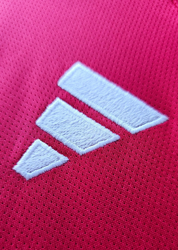 Close-up view of the white adidas logo on a red football shirt.