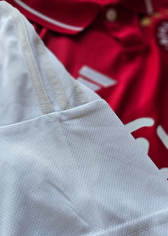 Close-up showing the white collar and texture of the signed football shirt with red background.