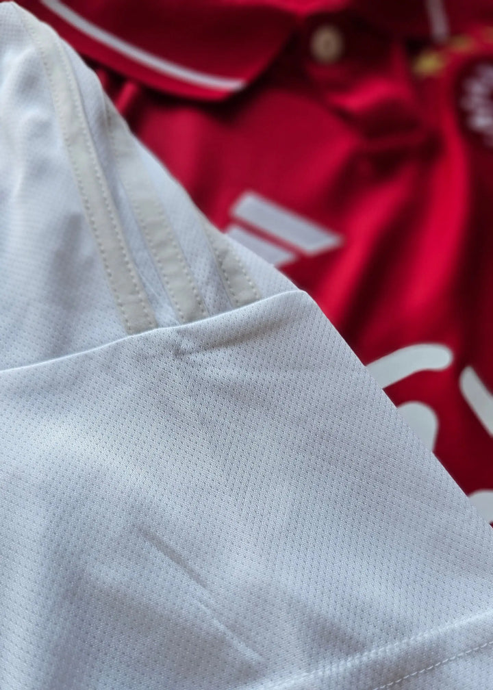 Close-up showing the white collar and texture of the signed football shirt with red background.