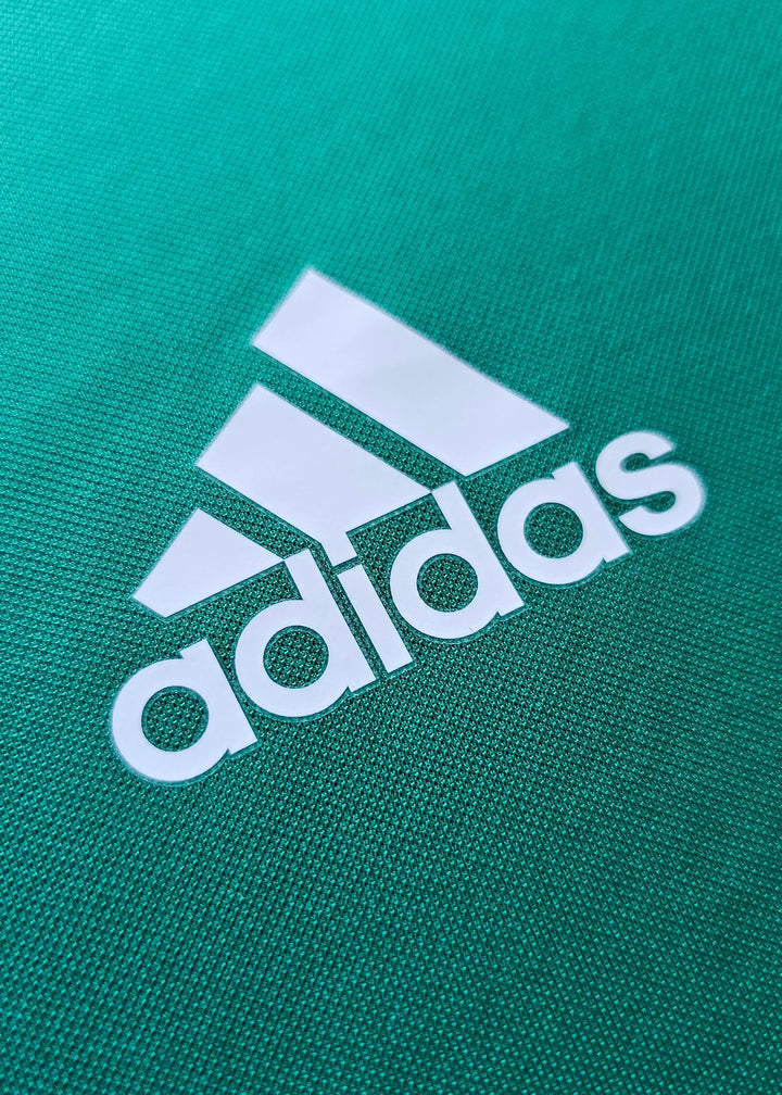 Close-up of white adidas logo on green fabric detailing the Signed Gianluigi Donnarumma jersey.