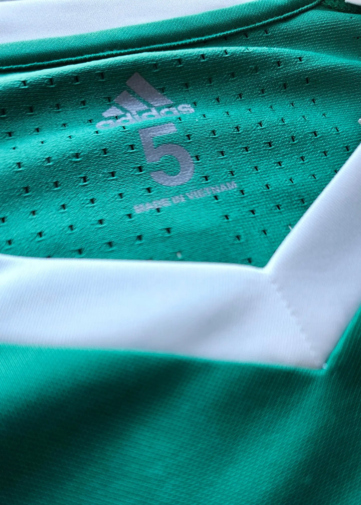 Close-up view of adidas logo and No. 5 on green football shirt with white accents.