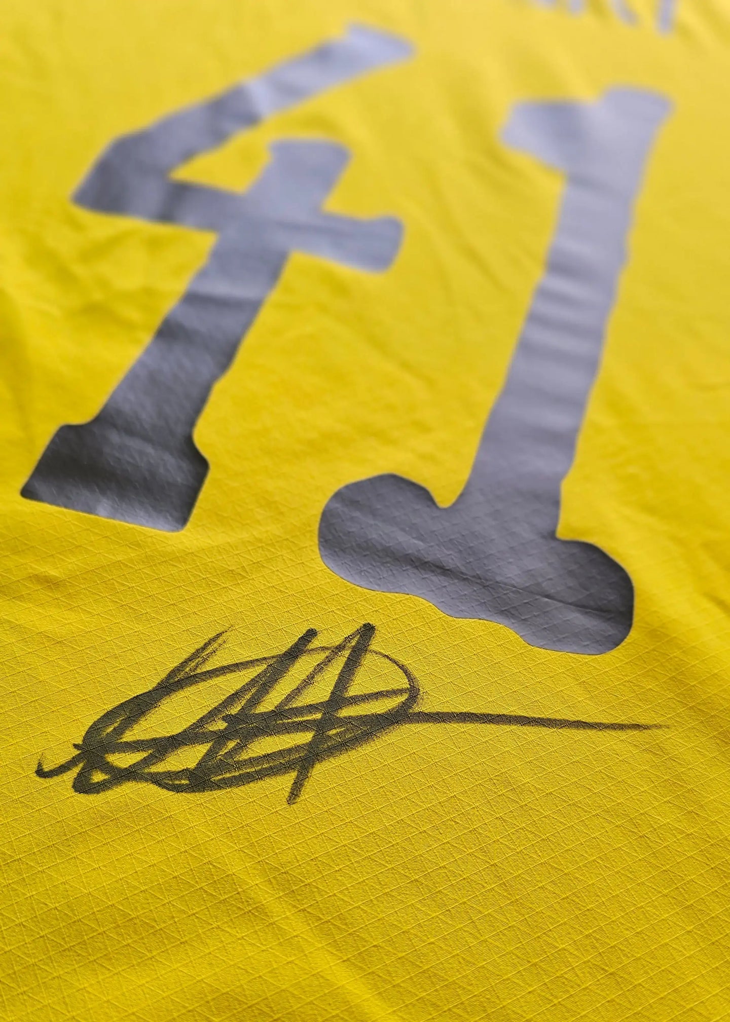 Close-up of signature on yellow shirt featuring No. 41 in grey.