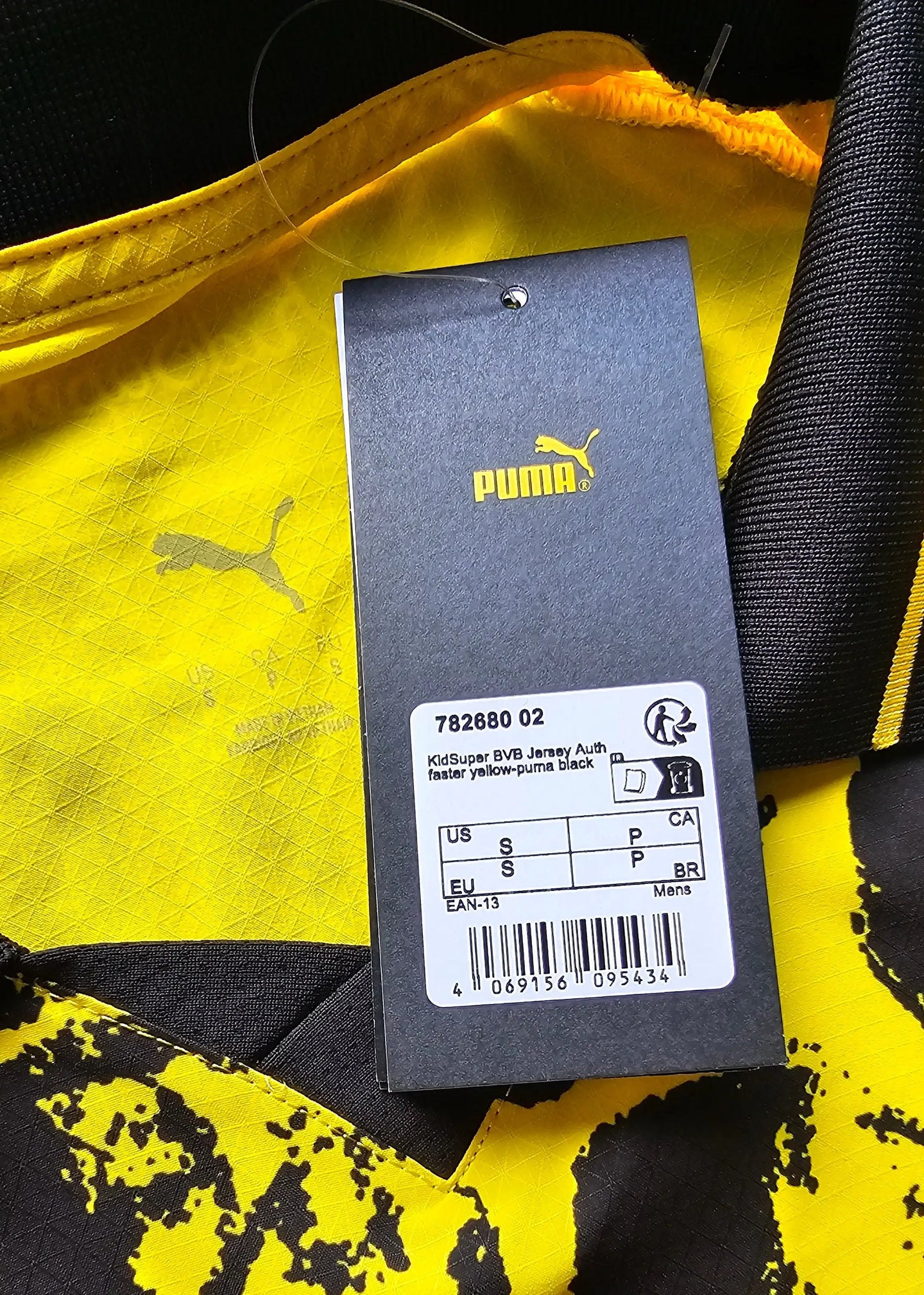 View showing yellow fabric with Puma logo and care tag details from the interior of the shirt.