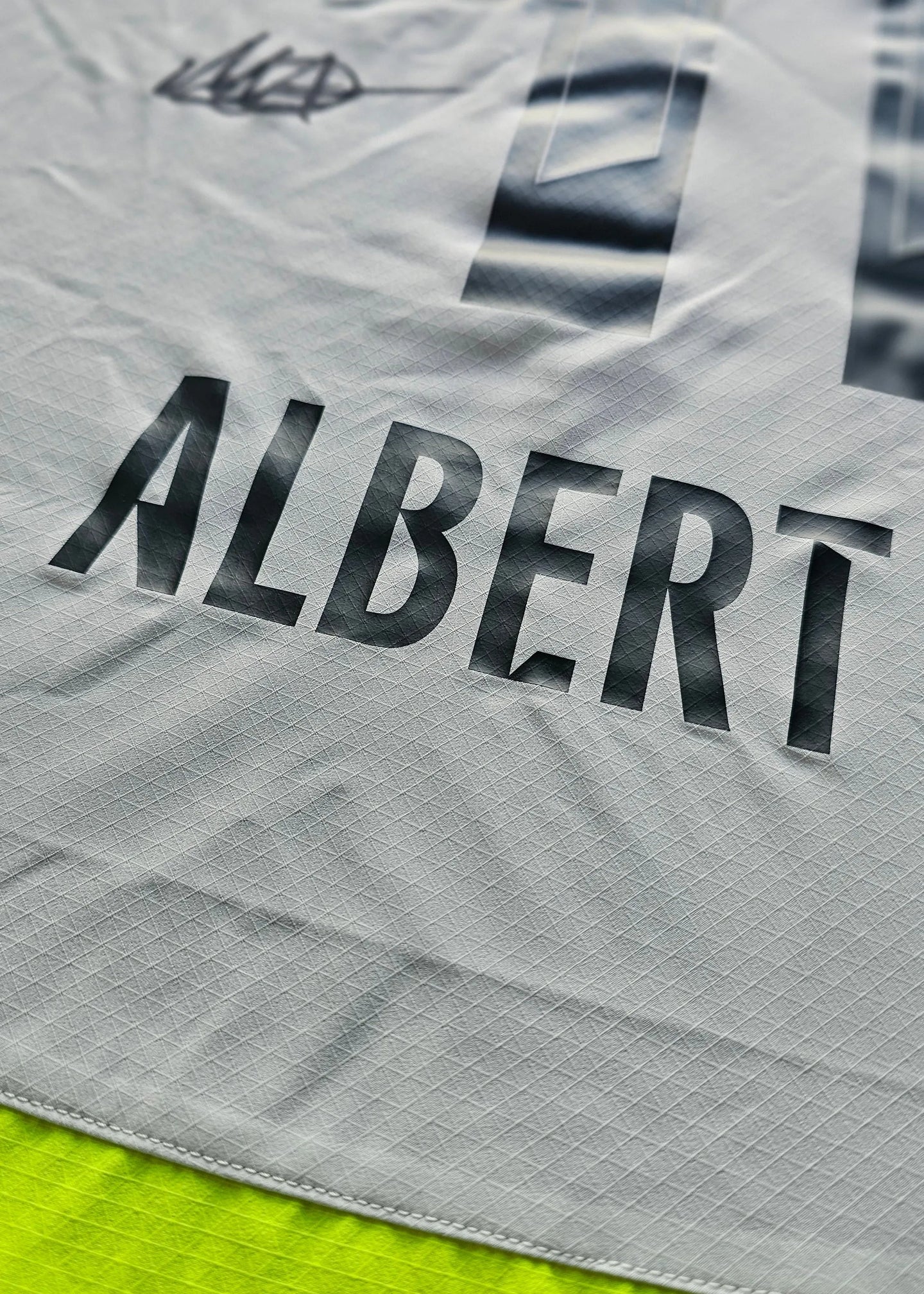 Detail view showing the name ALBERT and the number 1 on a grey football shirt.
