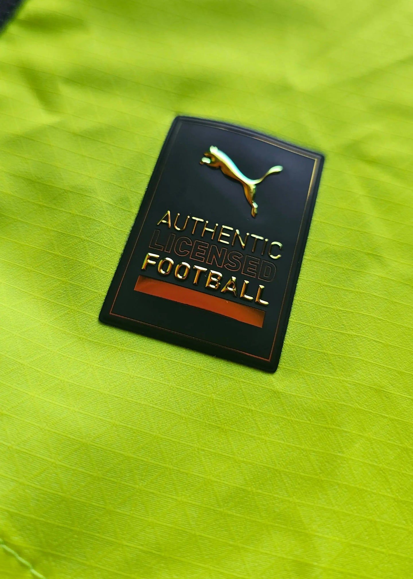 Close-up of the Puma label showing 'AUTHENTIC LICENSED FOOTBALL' on a bright yellow background.