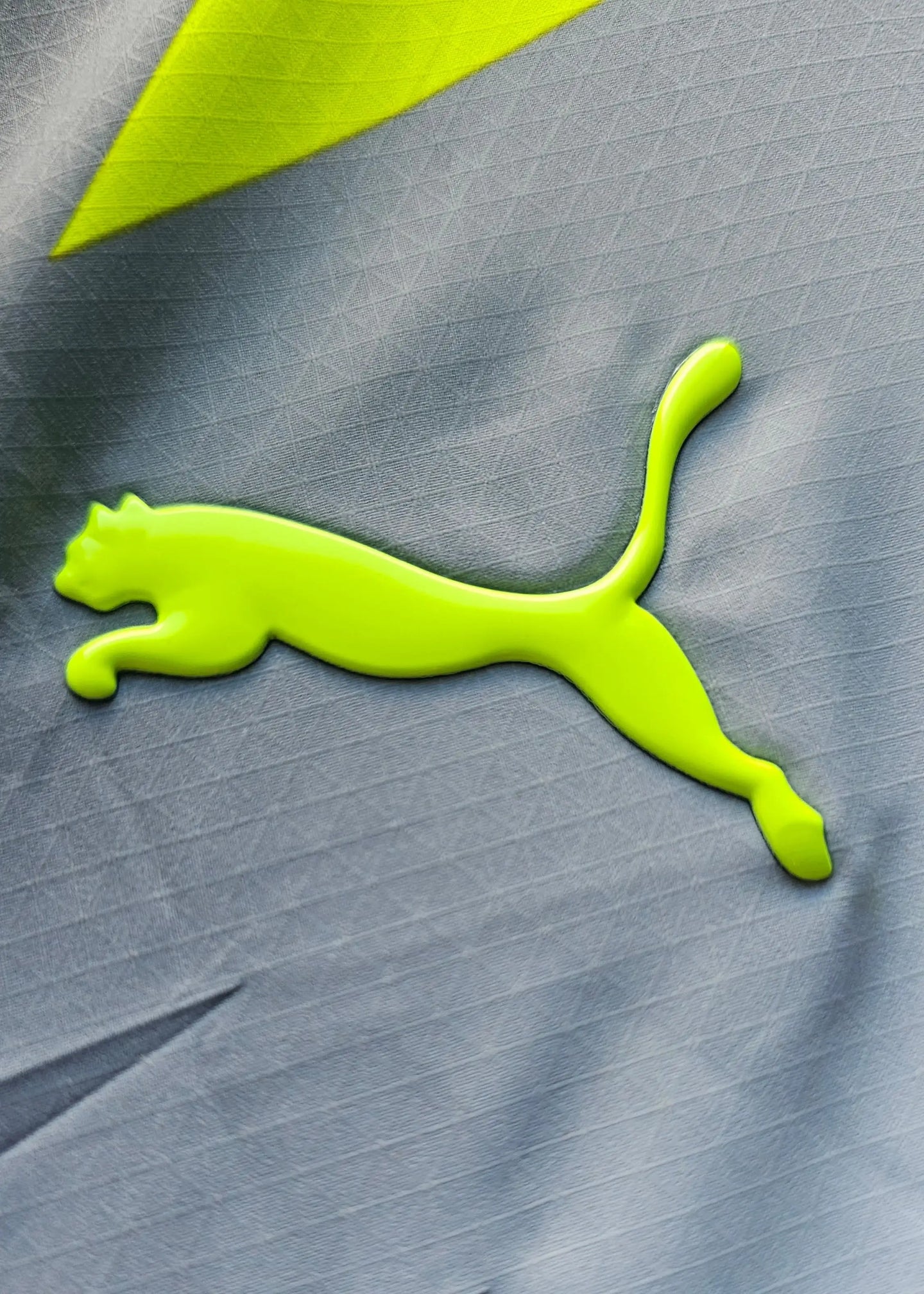 Detail showing the neon green Puma logo on the signed Mathis Albert Dortmund away shirt.
