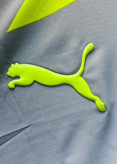 Detail showing the neon green Puma logo on the signed Mathis Albert Dortmund away shirt.