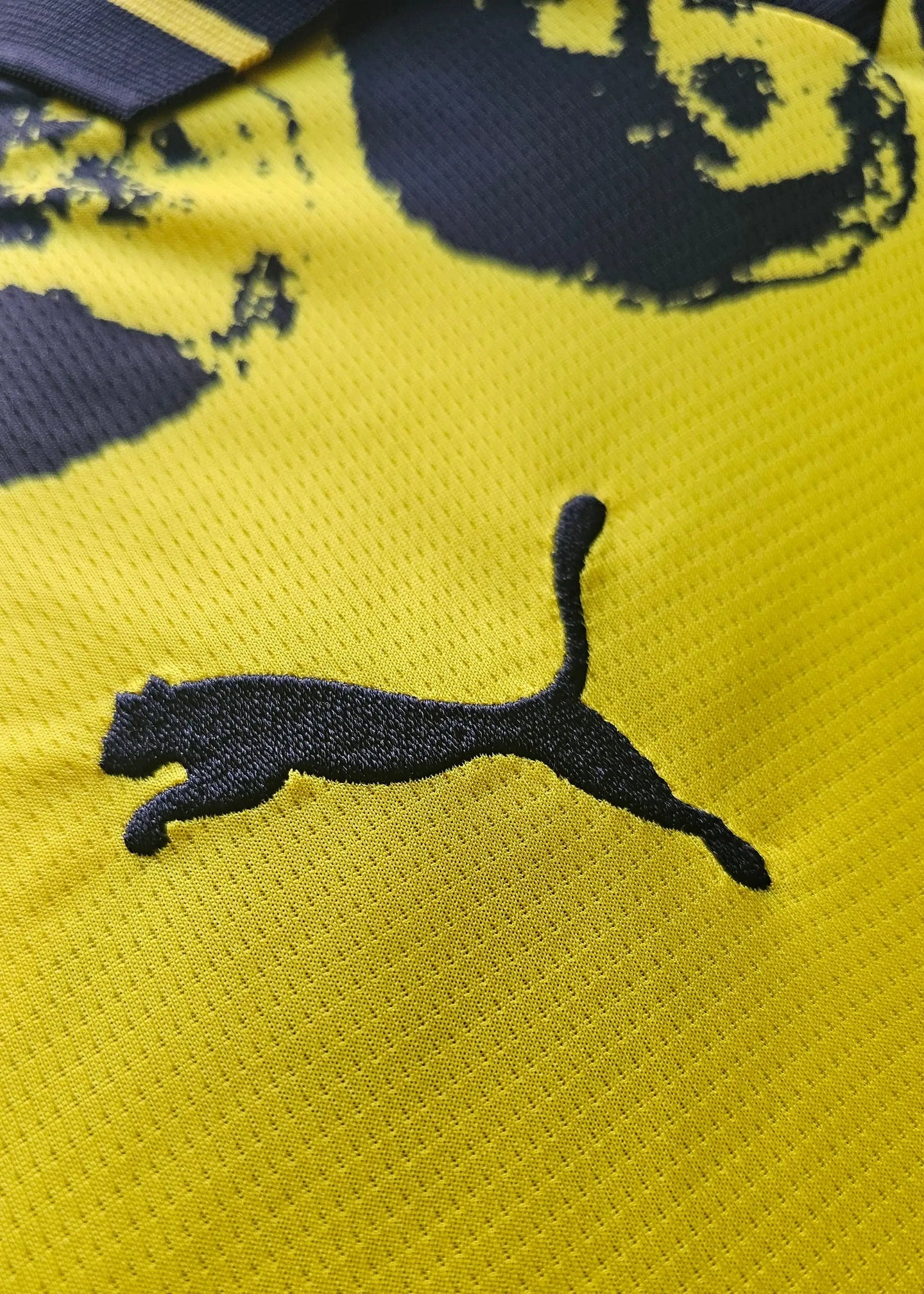 Detail showing the black Puma logo on a yellow background.