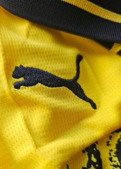 Close-up view of the Puma logo on the signed football shirt in yellow and black.