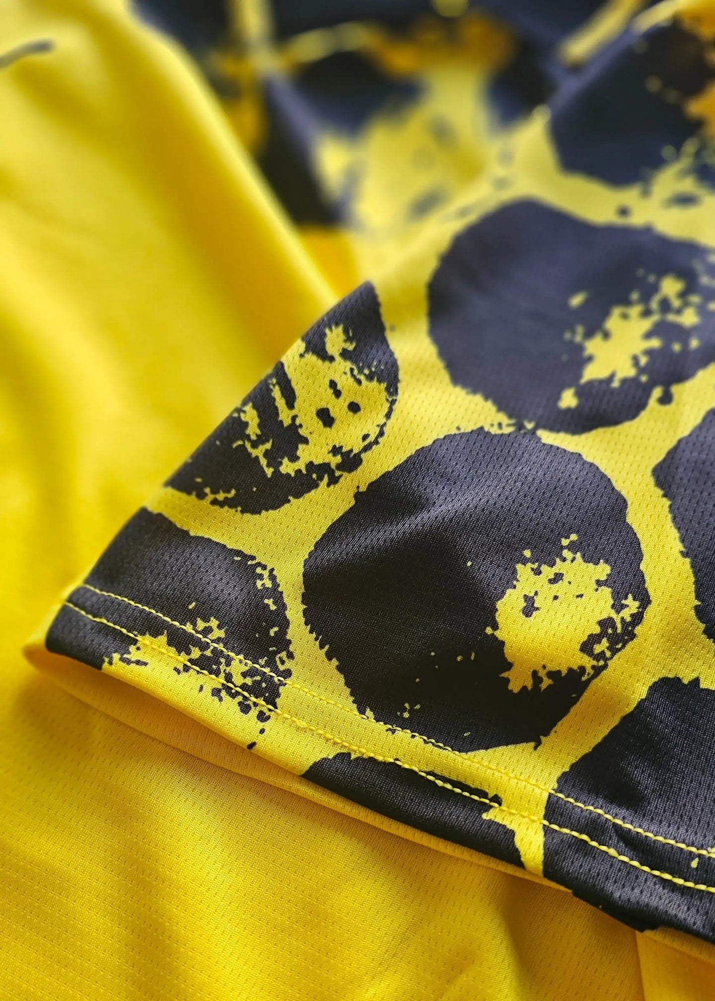 Detail view showcasing the signature and black-yellow design on the signed football shirt.